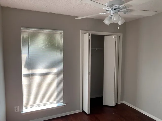 an empty room with wooden floor closet and windows