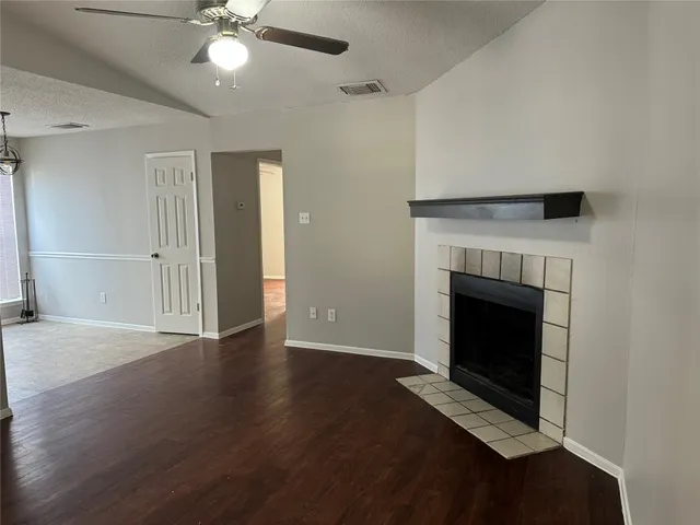 a view of an empty room with wooden floor and a fireplace