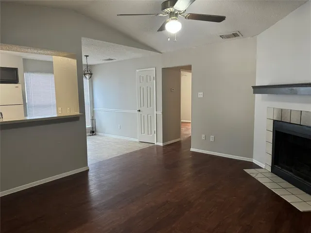 a view of an empty room with wooden floor fireplace and a window