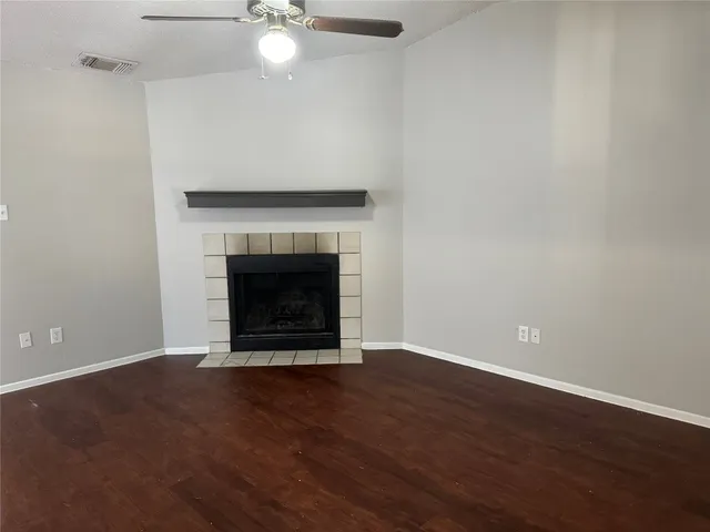 a view of an empty room with wooden floor fireplace and a window