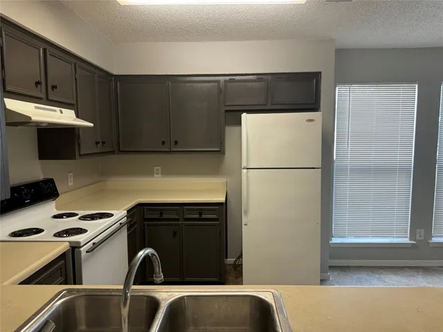 a kitchen with a refrigerator and a stove top oven