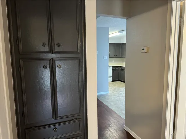 a view of a hallway with wooden floor and cabinet