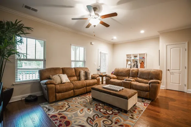 a living room with furniture a flat screen tv and wooden floor