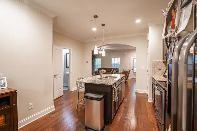 a kitchen with stainless steel appliances granite countertop a stove top oven a sink dishwasher a dining table and chairs with wooden floor