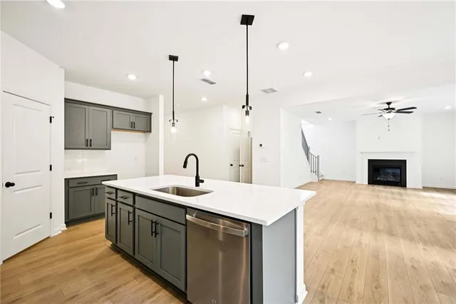 a kitchen with stainless steel appliances granite countertop a sink a stove a refrigerator and island with wooden floor