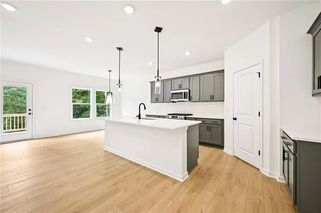 a large kitchen with kitchen island a sink wooden floor and stainless steel appliances