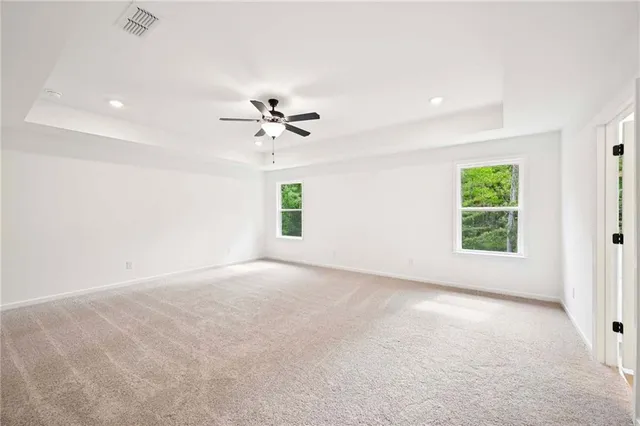 an empty room with chandelier fan and windows