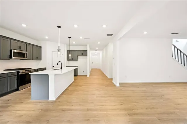 a large kitchen with a sink stainless steel appliances and white cabinets