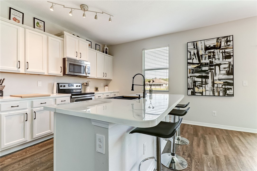 45170 Dutton Way Callahan, FL 32011 - Photo 11 of 35 a kitchen with stainless steel appliances kitchen island a stove a sink a refrigerator and cabinets
