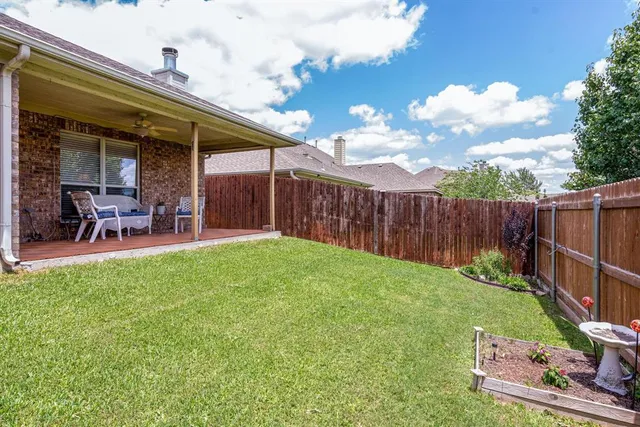 a brick house with a yard plants and wooden fence