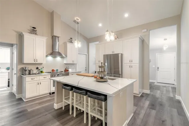 a kitchen with a sink a stove a refrigerator and white cabinets with wooden floor
