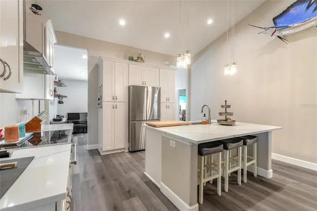 a kitchen with stainless steel appliances a table chairs refrigerator and sink
