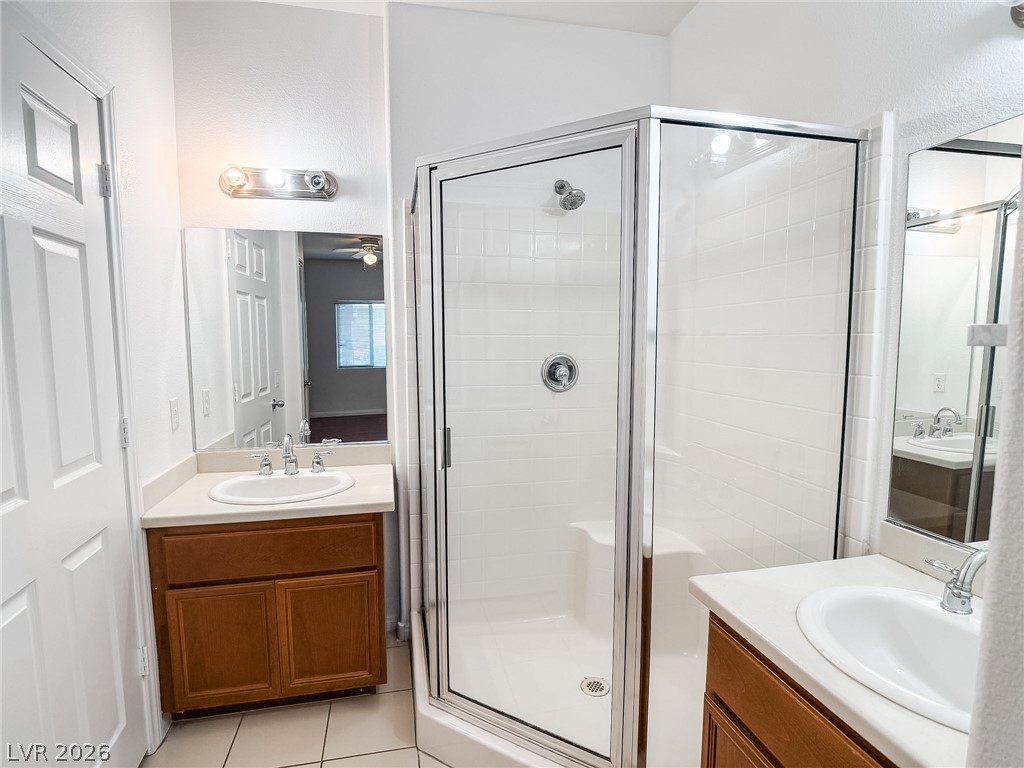 7701 West Robindale Road, Unit 110 Las Vegas, NV 89113 - Photo 10 of 21 Dual vanity sinks flank a pristine glass-enclosed shower, creating a functional bathroom space.