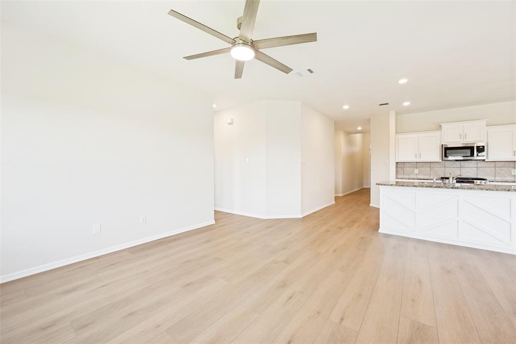 857 Watson Way Crowley, TX 76036 - Photo 2 of 25 Open-concept living area featuring wood-finish flooring, a modern ceiling fan with integrated lighting, recessed lighting, and a kitchen island with decorative paneling and a light-toned countertop