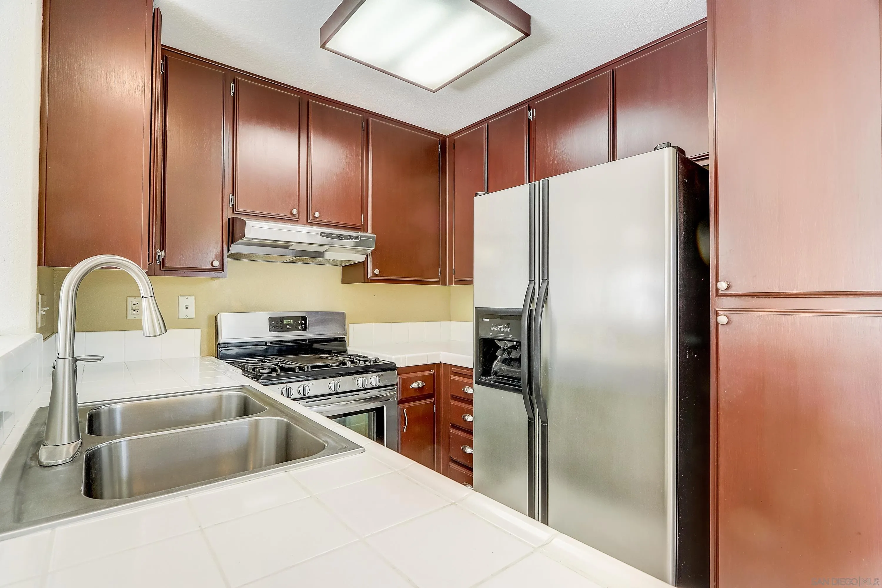405 Ribbon Beach Way, Unit 249 Oceanside, CA 92058 - Photo 8 of 34 a kitchen with stainless steel appliances a refrigerator a stove a sink and a refrigerator