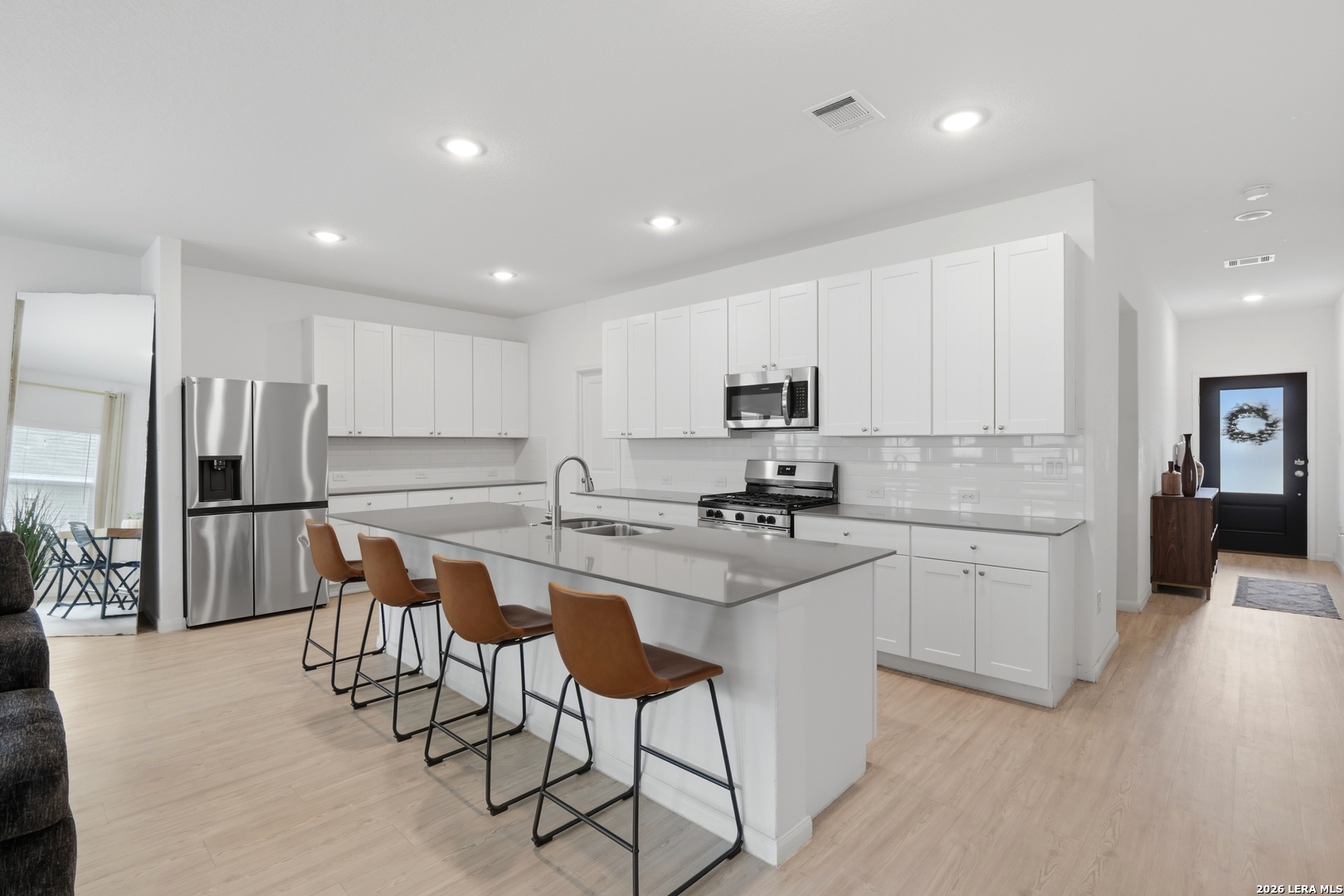 14919 Rhyolite Way Elmendorf, TX 78112 - Photo 5 of 26 a kitchen with stainless steel appliances a stove a sink a refrigerator white cabinets and wooden floor