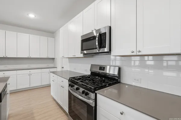 a kitchen with stainless steel appliances granite countertop white cabinets a stove top oven and sink