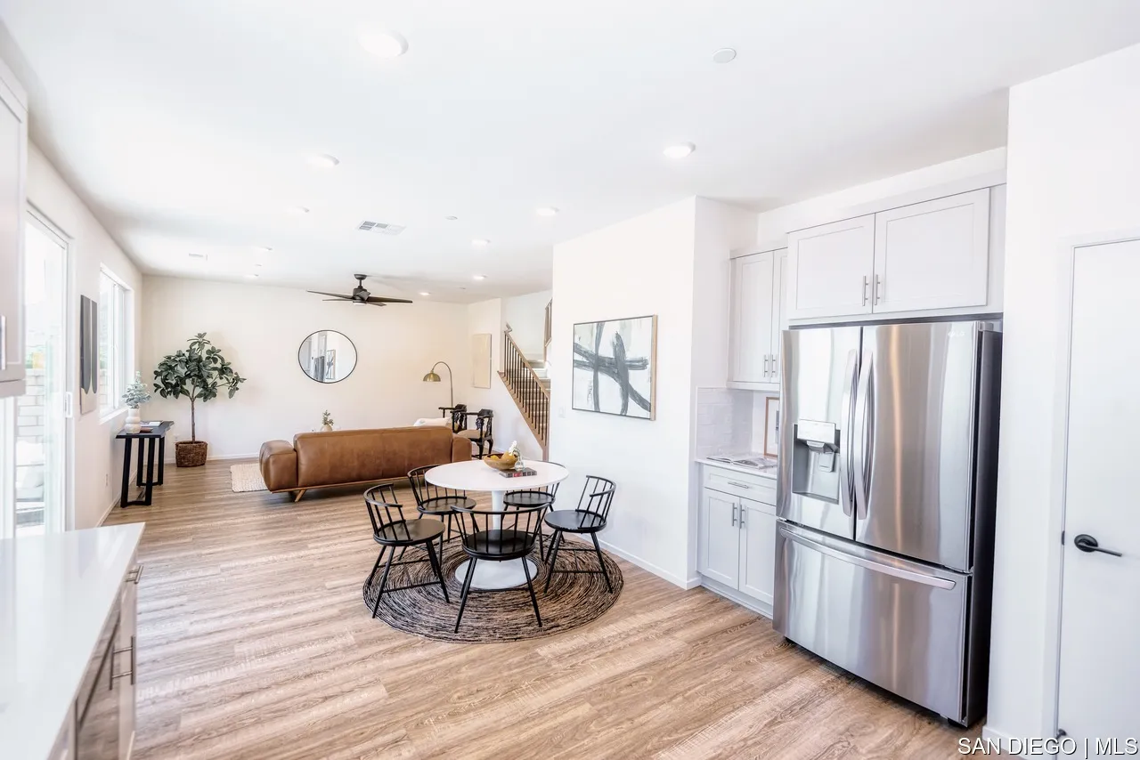 229 Paddock Lane Fallbrook, CA 92028 - Photo 10 of 33 a kitchen with stainless steel appliances a refrigerator a stove a dining table and chairs with wooden floor