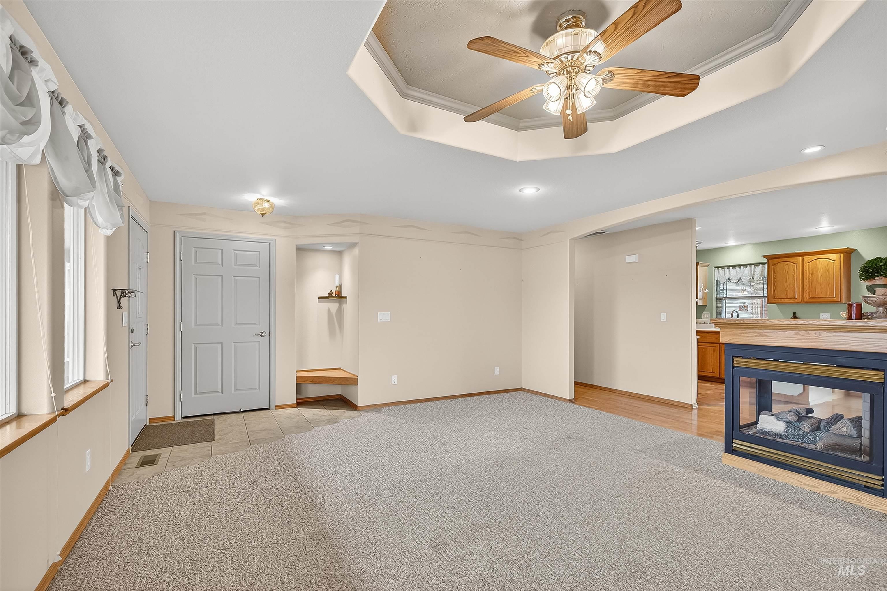 1324 Setlow Court Clarkston, WA 99403 - Photo 14 of 49 Unfurnished living room with light carpet, a tray ceiling, a ceiling fan, recessed lighting, and crown molding