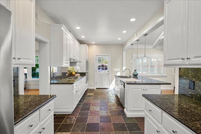 a large kitchen with granite countertop lots of counter space and stainless steel appliances