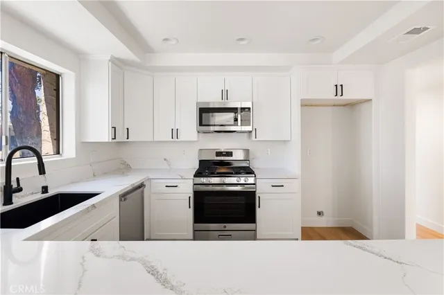 a kitchen with stainless steel appliances a stove a sink and a refrigerator