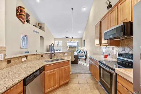 a kitchen with stainless steel appliances granite countertop a sink a stove and a wooden floors