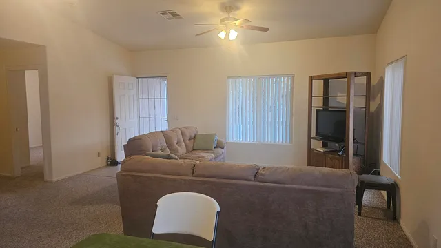 a living room with furniture and a ceiling fan