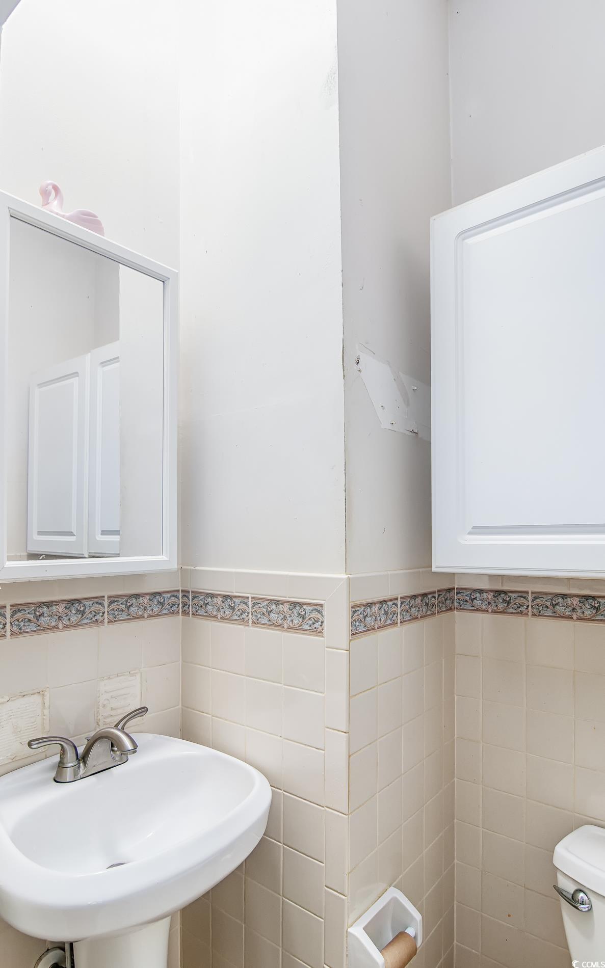 1019 Prince Street Georgetown, SC 29440 - Photo 11 of 22 Bathroom featuring a sink, toilet, tile walls, and wainscoting