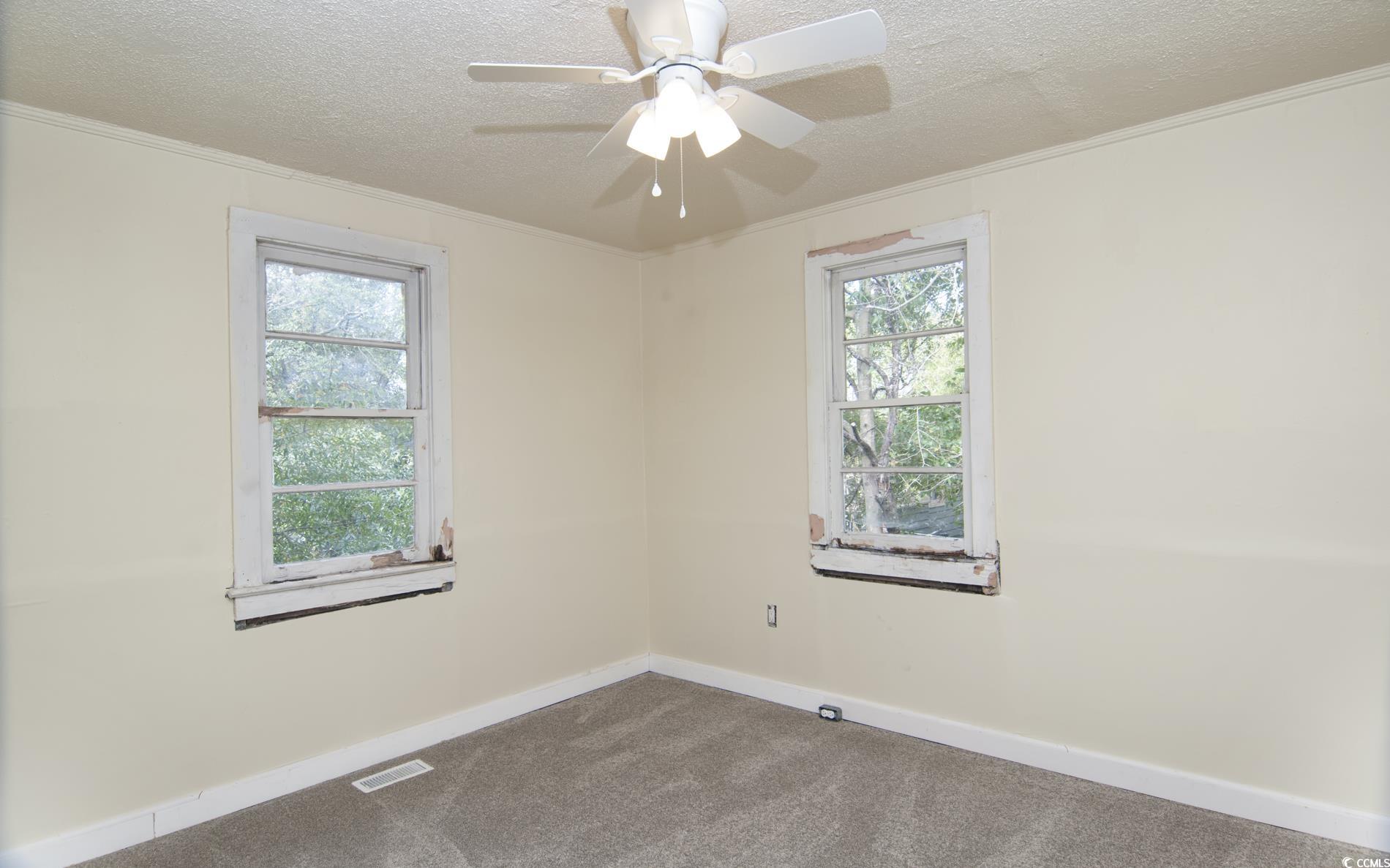 1019 Prince Street Georgetown, SC 29440 - Photo 21 of 22 Carpeted empty room with a ceiling fan, baseboards, visible vents, ornamental molding, and a textured ceiling