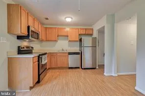 a kitchen with stainless steel appliances granite countertop a refrigerator a stove top oven a sink and dishwasher with wooden floor