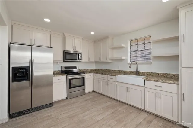 a kitchen with granite countertop white cabinets and stainless steel appliances
