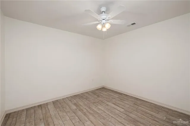 an empty room with wooden floor and fan
