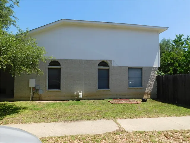 a backyard of a house with plants and a tree