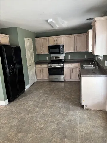 a kitchen with granite countertop a refrigerator and a stove top oven