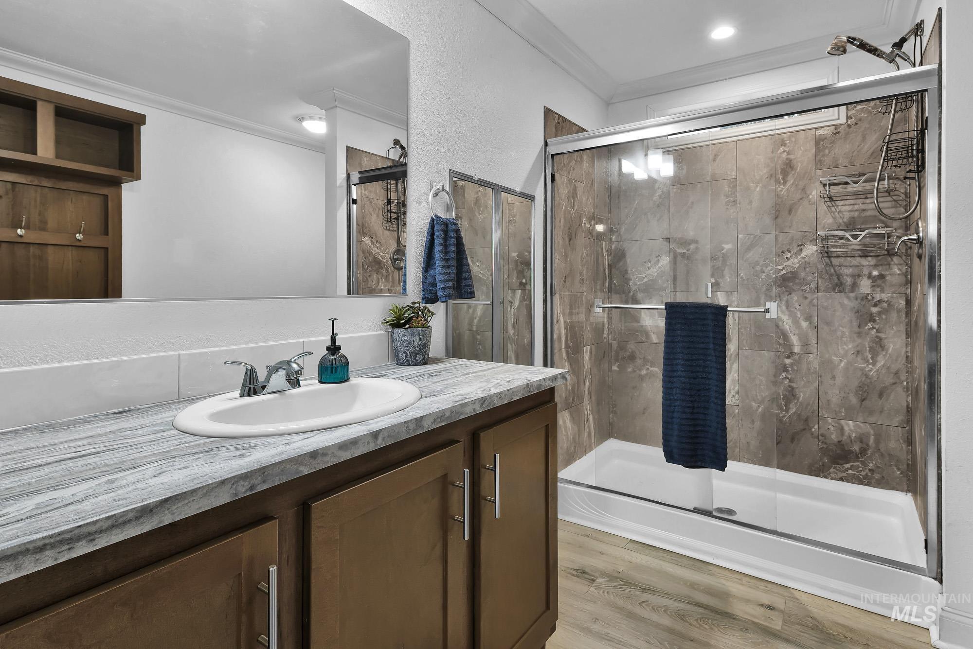 8483 West Irving Lane Boise, ID 83704 - Photo 16 of 40 Full bath featuring vanity, a shower stall, ornamental molding, light wood-style floors, and a textured wall