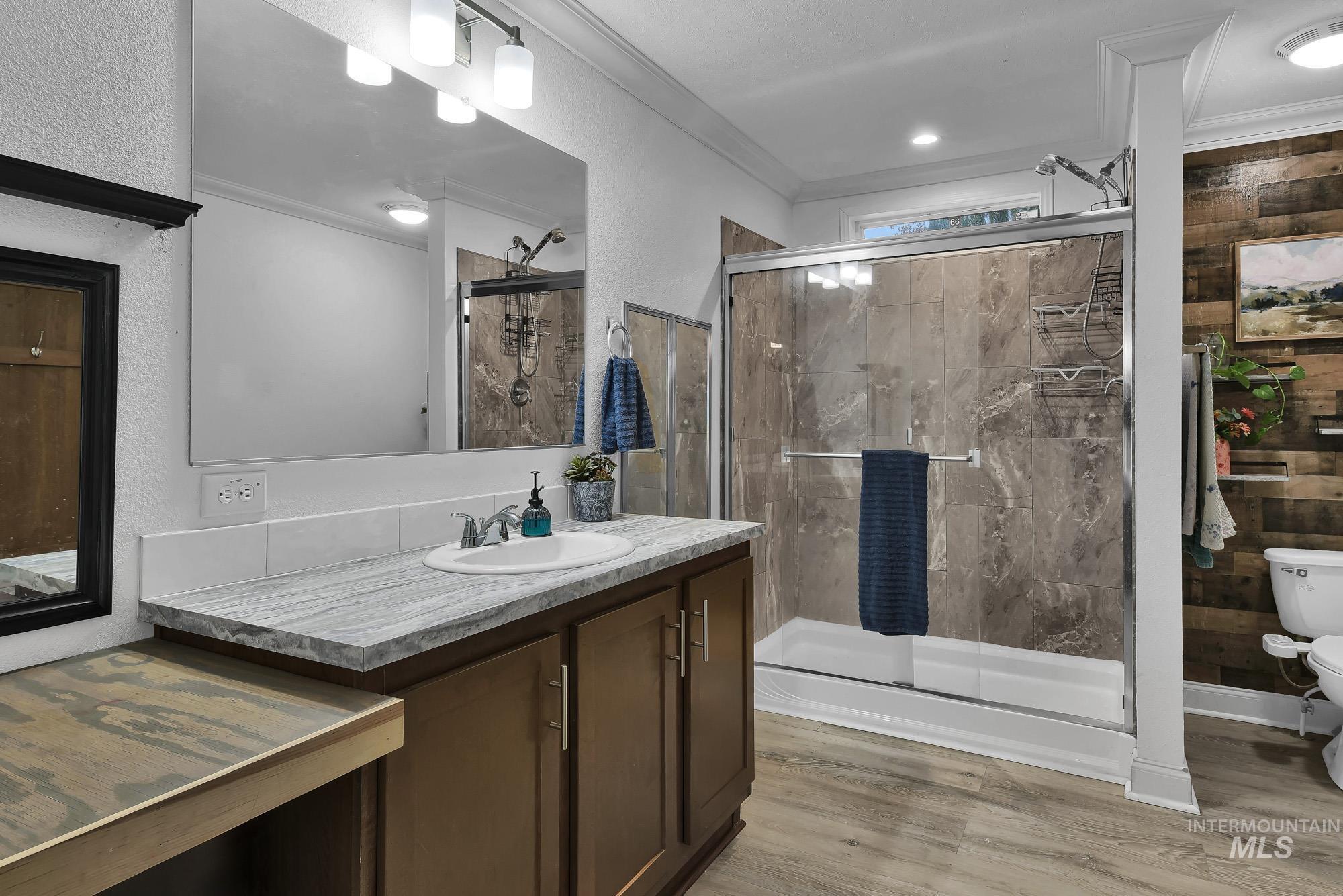 8483 West Irving Lane Boise, ID 83704 - Photo 16 of 40 Bathroom featuring vanity, ornamental molding, a stall shower, light wood-style flooring, and a textured wall