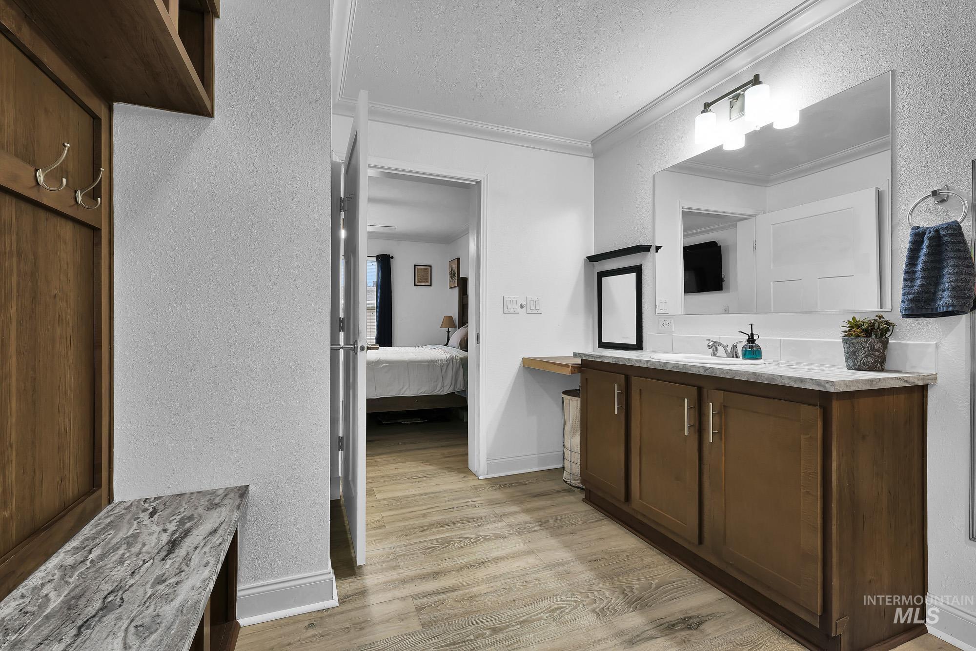 8483 West Irving Lane Boise, ID 83704 - Photo 17 of 40 Ensuite bathroom featuring a textured wall, vanity, light wood-type flooring, and ornamental molding