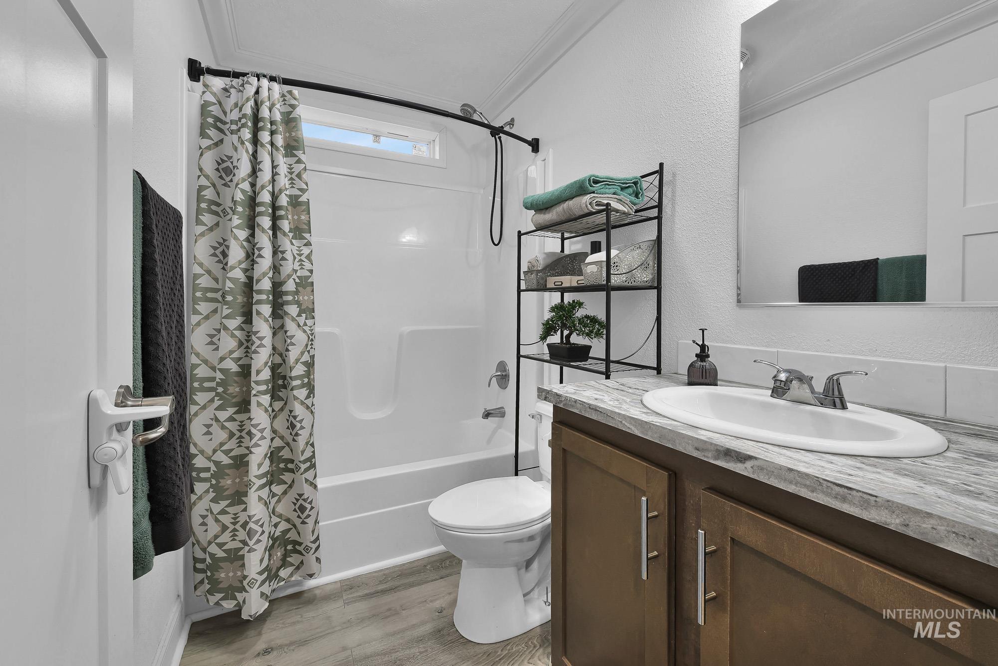 8483 West Irving Lane Boise, ID 83704 - Photo 24 of 40 Full bathroom with vanity, shower / bath combo with shower curtain, crown molding, light wood-type flooring, and a textured wall