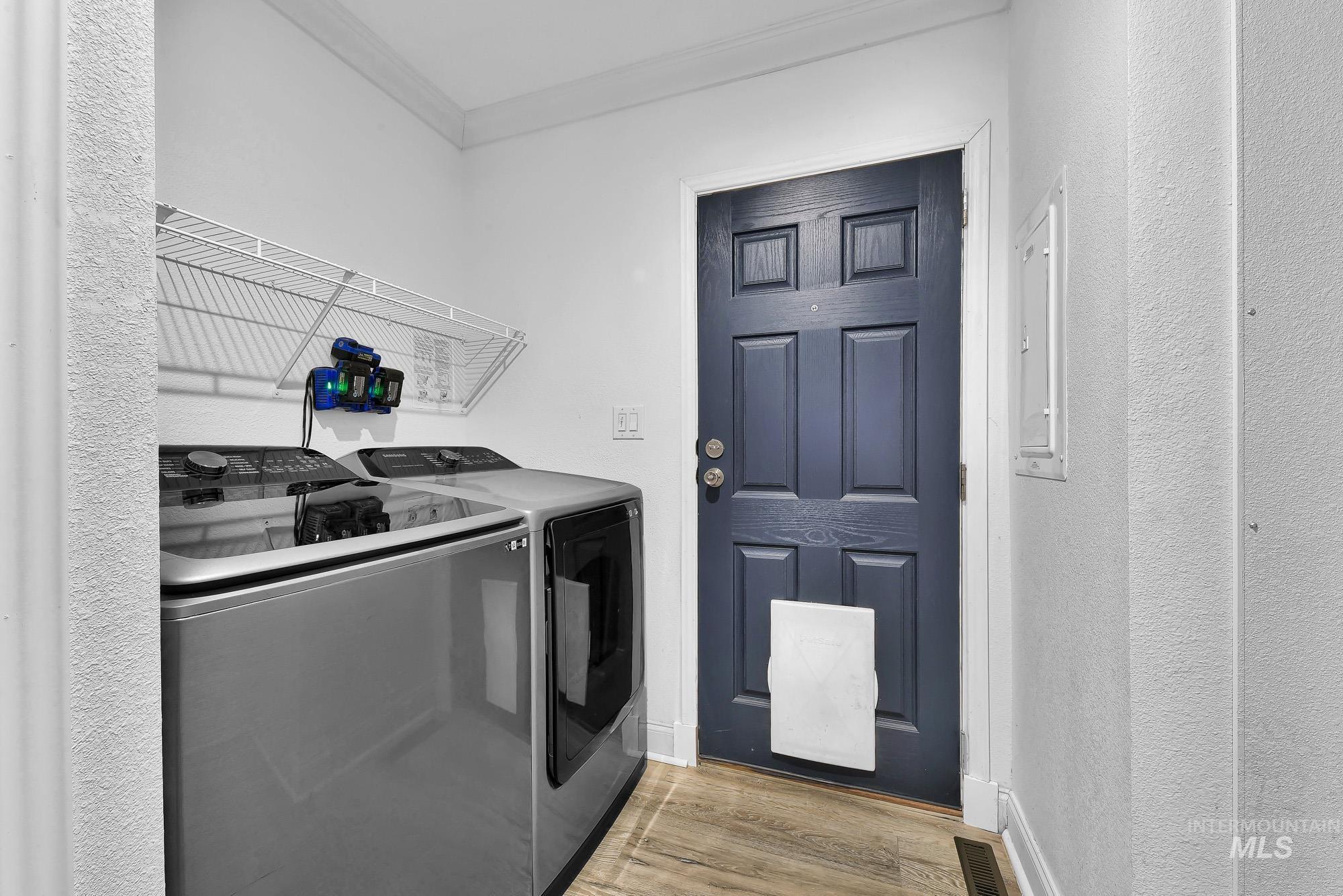 8483 West Irving Lane Boise, ID 83704 - Photo 26 of 40 Laundry area with a textured wall, light wood-style floors, ornamental molding, washer and dryer, and electric panel