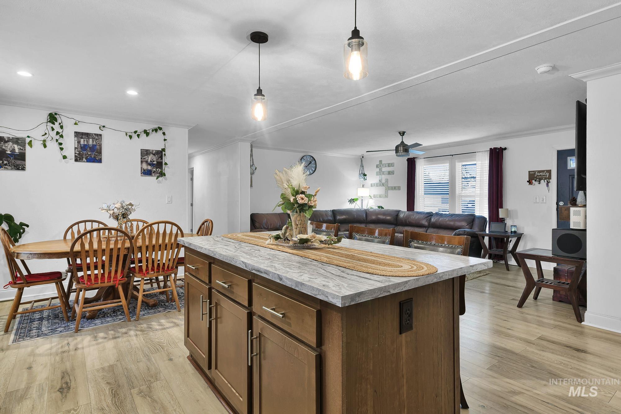 8483 West Irving Lane Boise, ID 83704 - Photo 10 of 40 Kitchen featuring a kitchen island, light wood finished floors, light countertops, dark brown cabinets, and ornamental molding