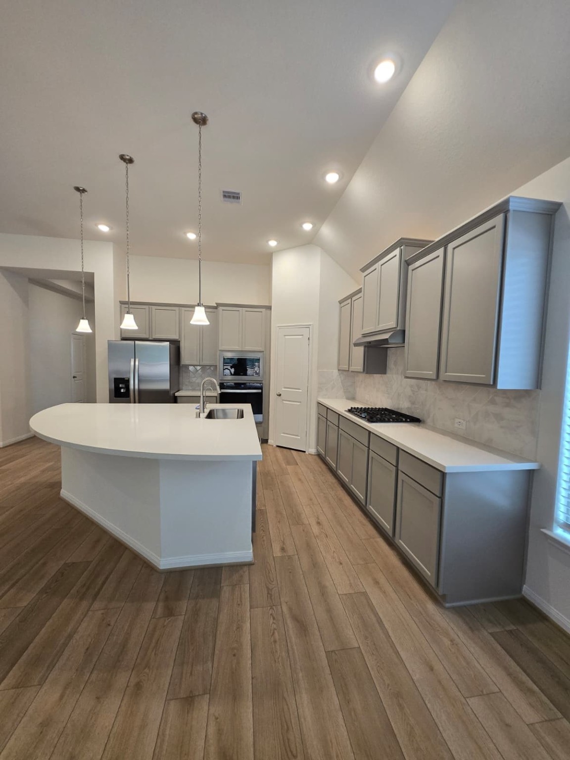 a large white kitchen with kitchen island a sink a stove and a wooden floors