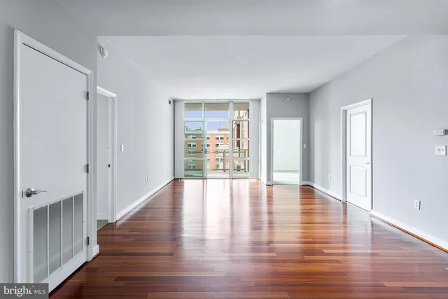 a view of an empty room with wooden floor and window