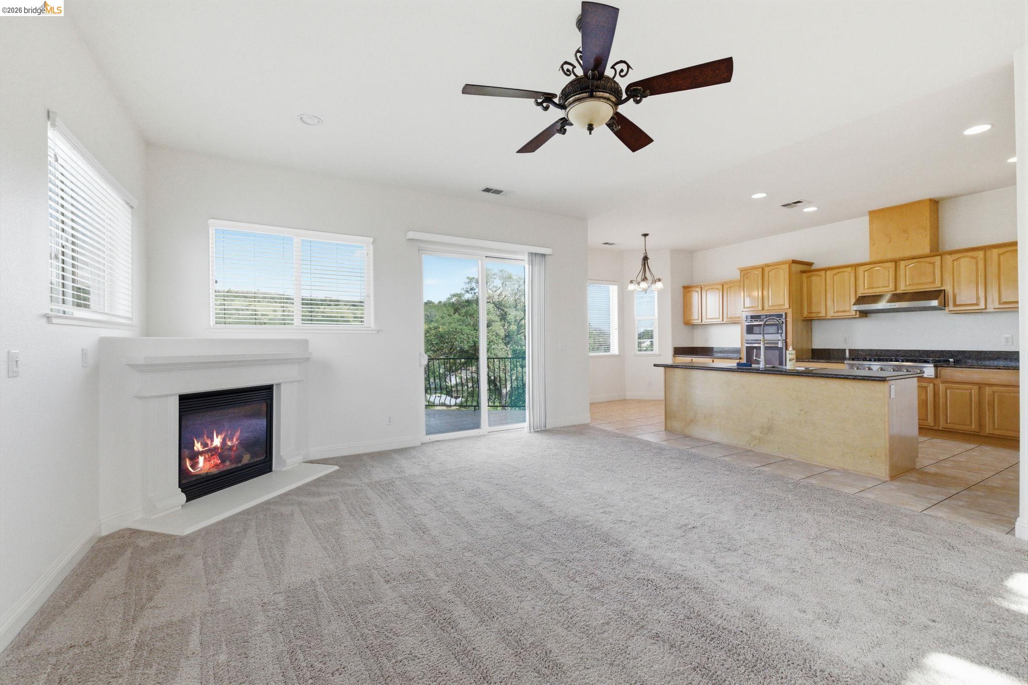 32 Apollo Lane Copperopolis, CA 95228 - Photo 11 of 58 Unfurnished living room with a ceiling fan, light carpet, a glass covered fireplace, suspended lighting, and light tile patterned flooring