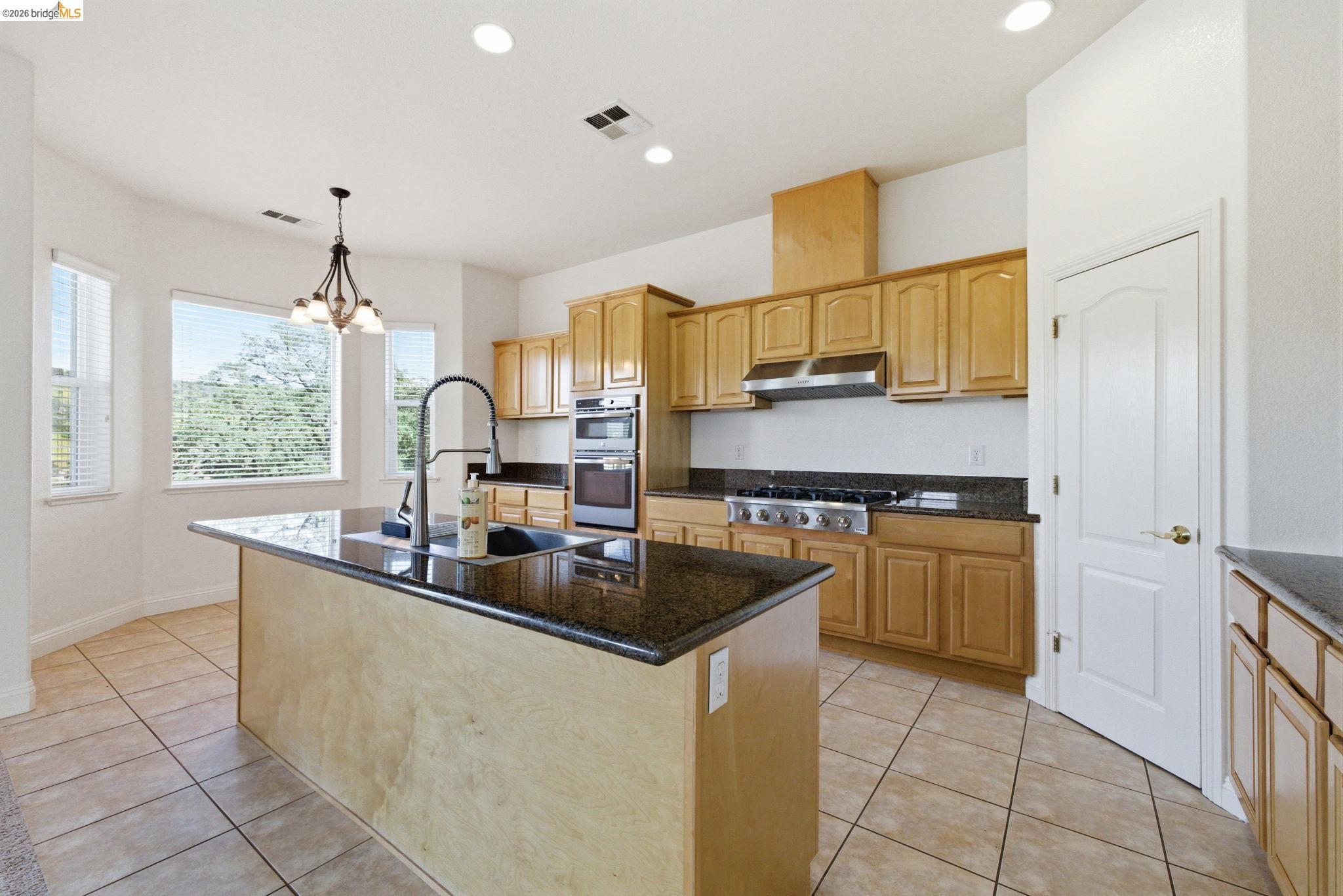 32 Apollo Lane Copperopolis, CA 95228 - Photo 15 of 58 Kitchen with light tile patterned flooring, an island with sink, hanging lights, dark stone counters, and stainless steel appliances