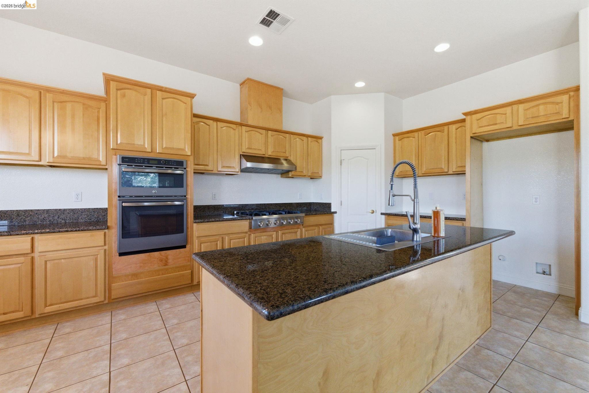 32 Apollo Lane Copperopolis, CA 95228 - Photo 16 of 58 Kitchen featuring a center island with sink, dark stone counters, light tile patterned floors, stainless steel appliances, and recessed lighting