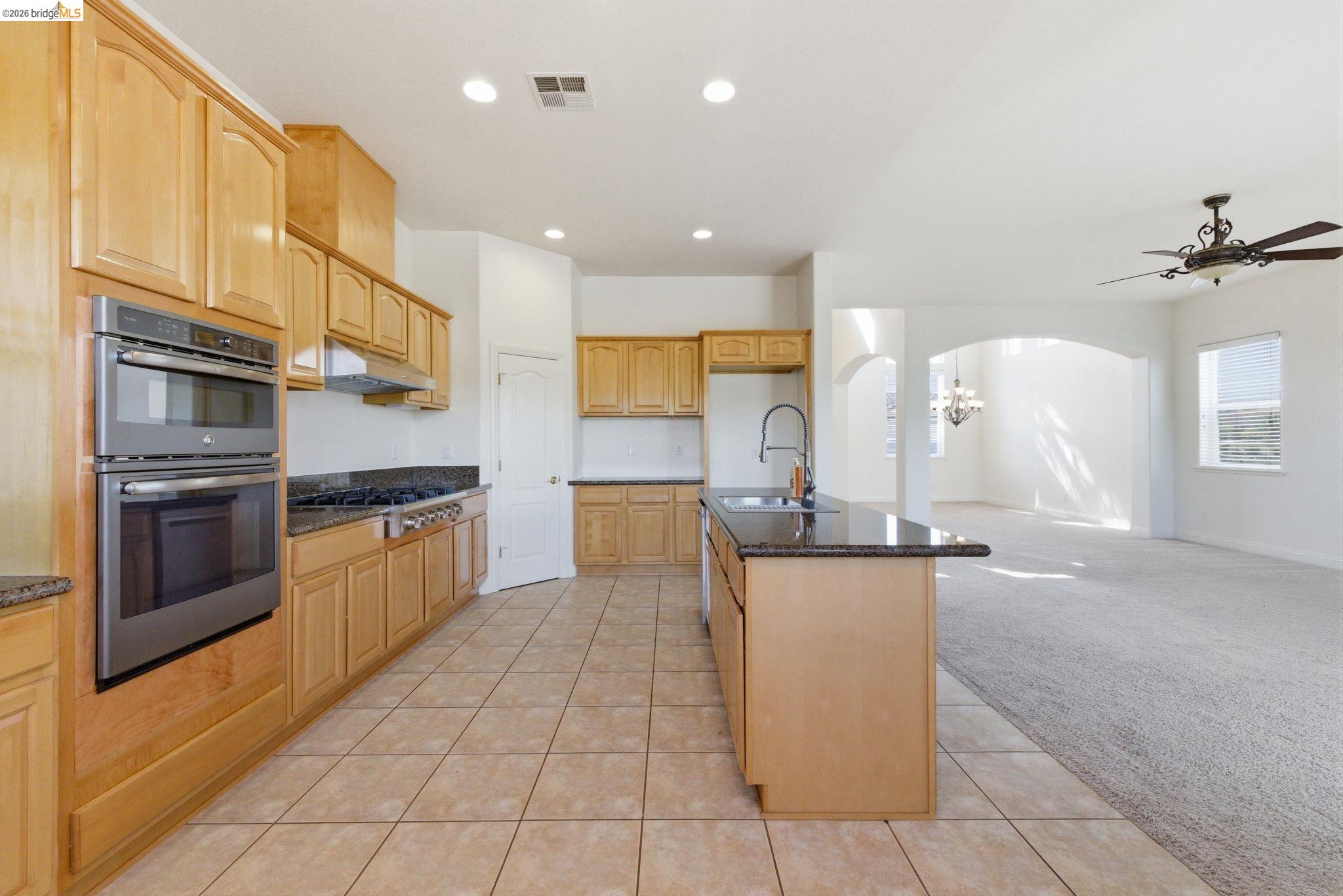 32 Apollo Lane Copperopolis, CA 95228 - Photo 17 of 58 Kitchen featuring light colored carpet, light tile patterned floors, arched walkways, stainless steel appliances, and dark stone countertops