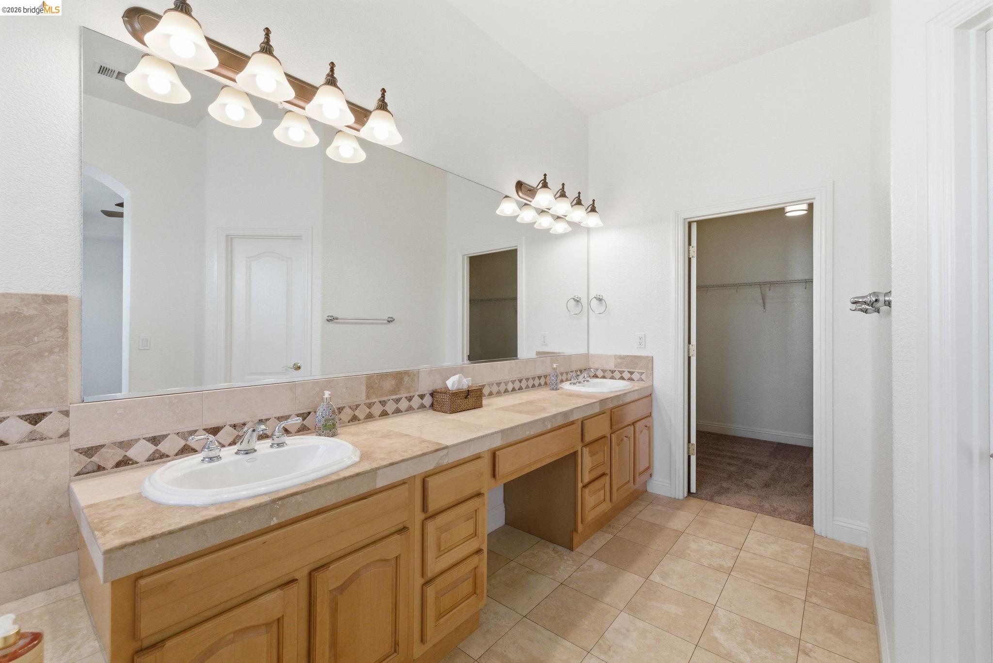 32 Apollo Lane Copperopolis, CA 95228 - Photo 29 of 58 Full bathroom featuring double vanity, light tile patterned floors, a spacious closet, and backsplash