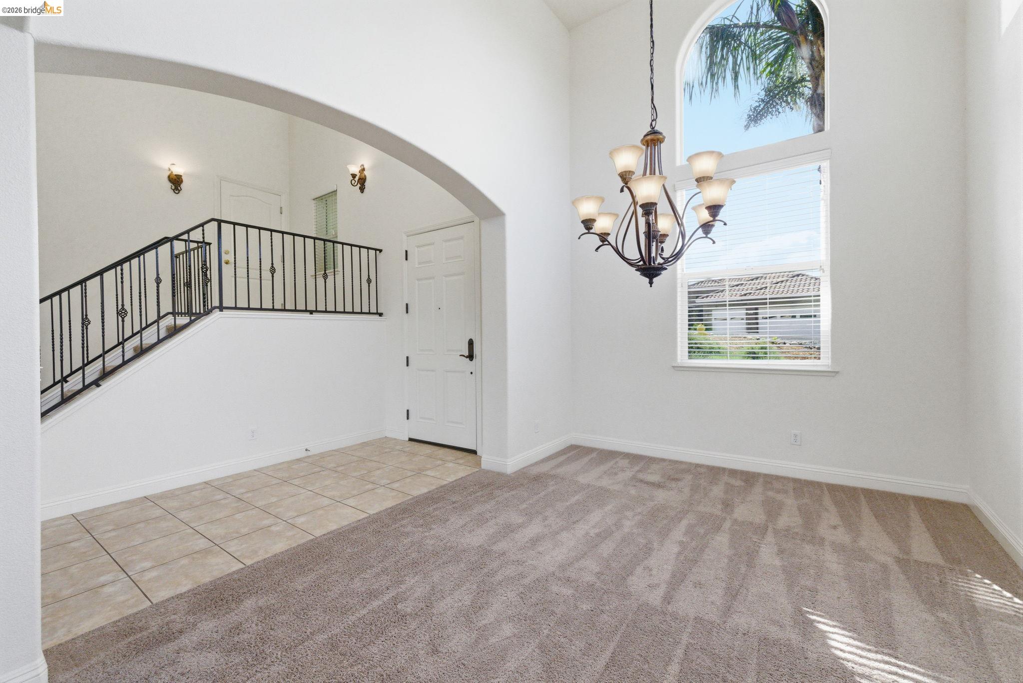 32 Apollo Lane Copperopolis, CA 95228 - Photo 7 of 58 Unfurnished dining area featuring suspended lighting, arched walkways, a high ceiling, light carpet, and light tile patterned floors