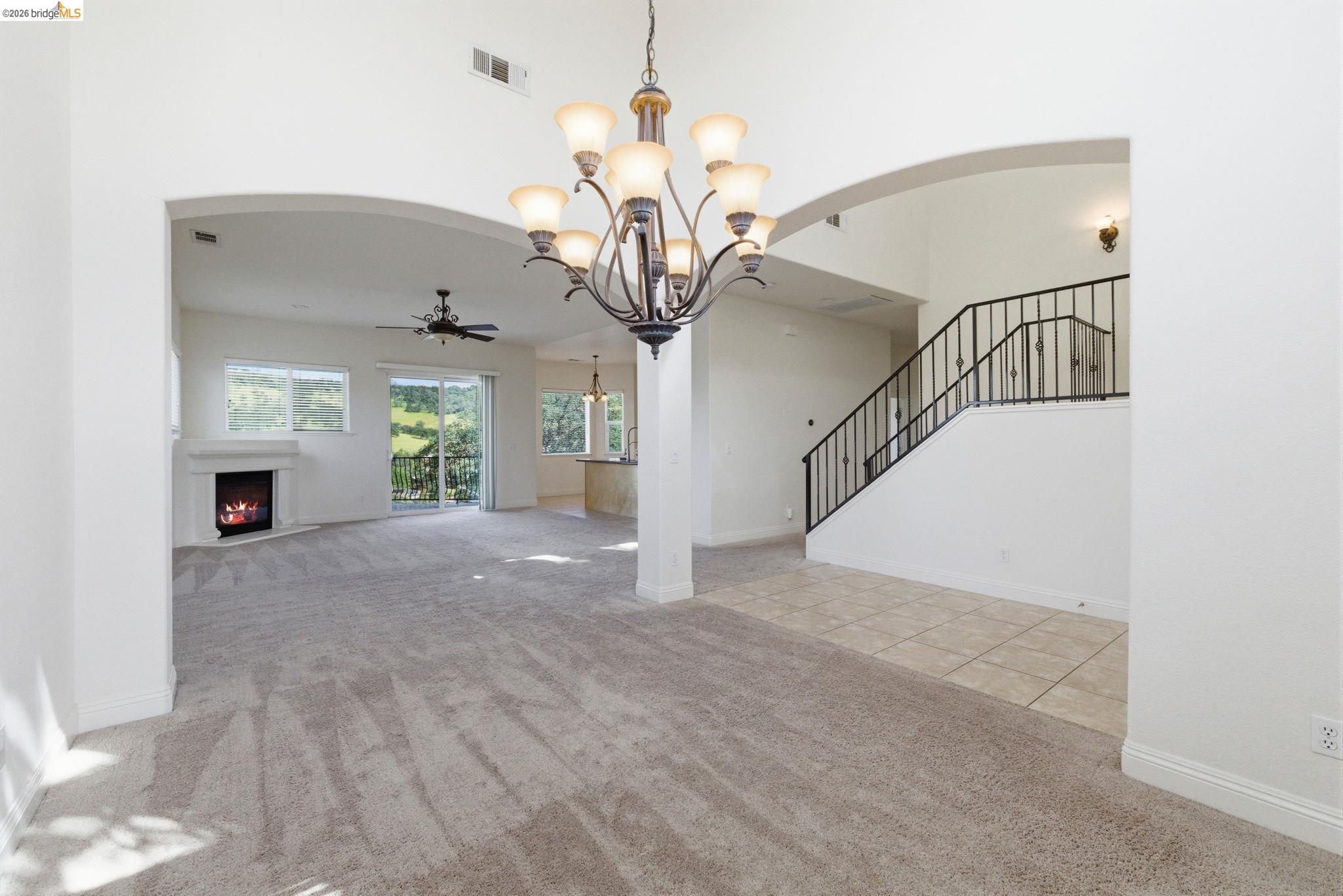 32 Apollo Lane Copperopolis, CA 95228 - Photo 8 of 58 Unfurnished living room with light carpet, arched walkways, a ceiling fan, a chandelier, and a high ceiling