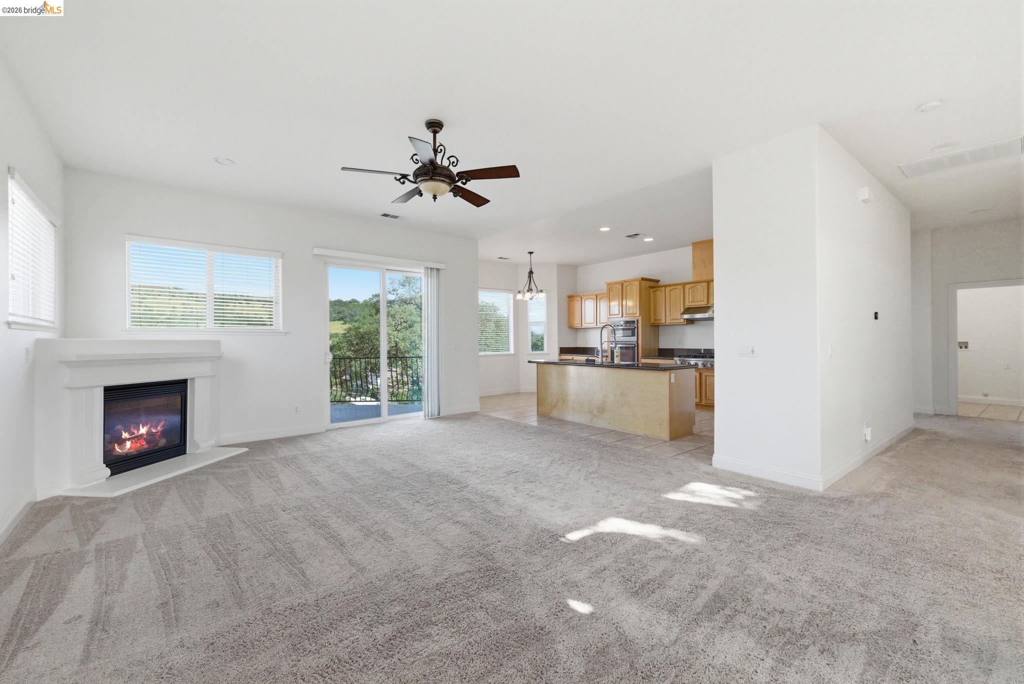 32 Apollo Lane Copperopolis, CA 95228 - Photo 10 of 58 Unfurnished living room featuring light colored carpet, ceiling fan, a glass covered fireplace, and a chandelier